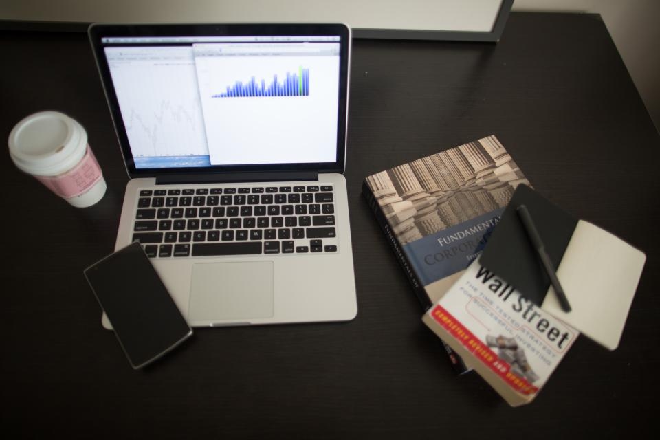 Laptop with a rising bar chart and finance books, illustrating building intelligence ROI for GCC SMEs