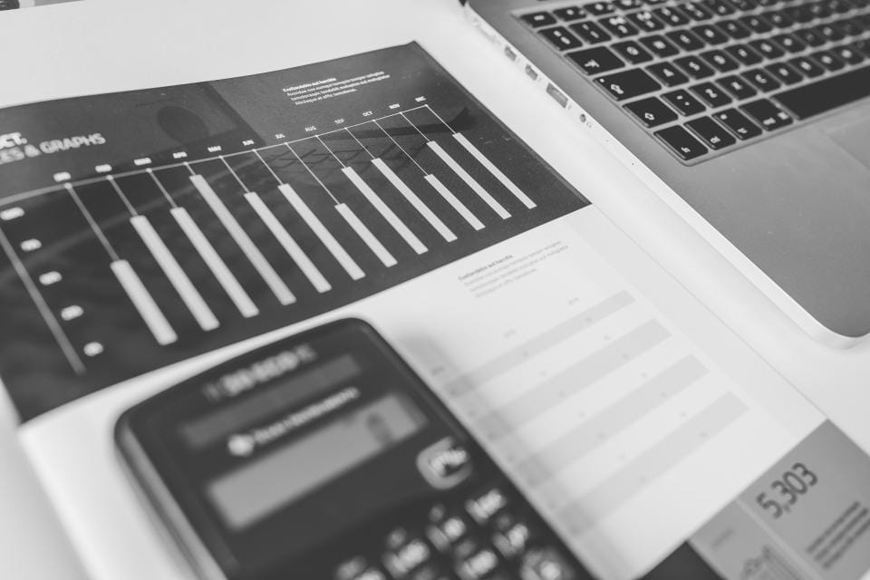 Financial report and calculator beside a laptop, showing how accounts payable AI agents process invoices